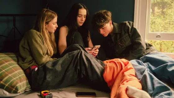 Photograph of three young people looking at a mobile phone.