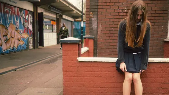 Photograph of a girl leaning against a wall.
