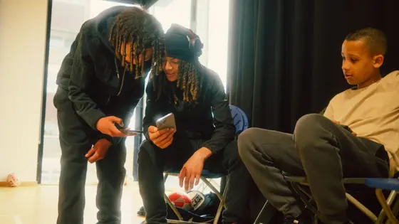 Photograph of three teenagers using their phones.