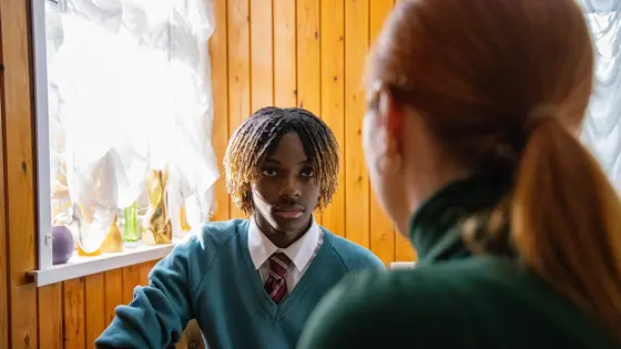 Teenage boy sat at a table with a parent