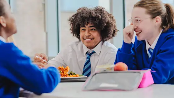 A school girl and school boy sat next to each other at a lunch table