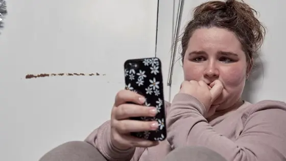 A young person sitting down and looking at a mobile phone