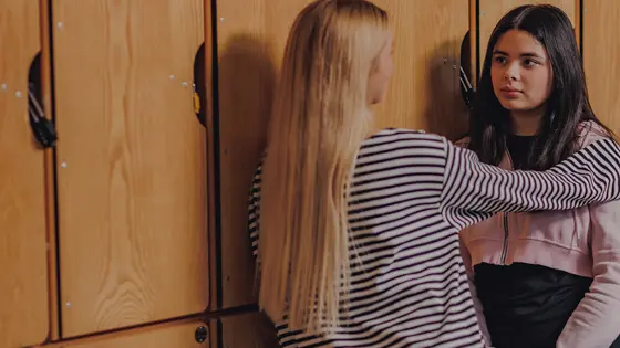 Two teenage girls talking in a school